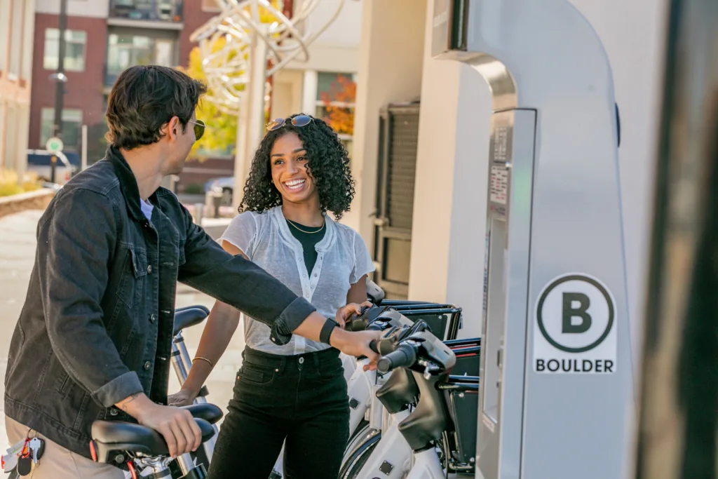 a woman showing a man how to undock a bike share bicycle